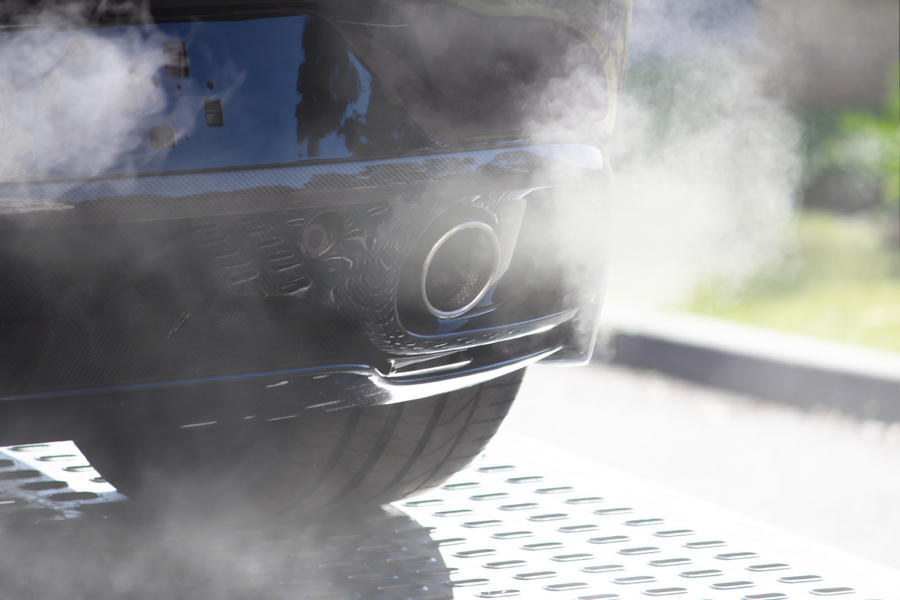 White smoke billowing from the exhaust of a navy-blue car